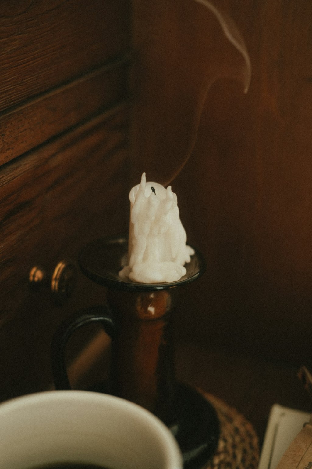 Home protection spell: a white candle with smoke rising in a dark room