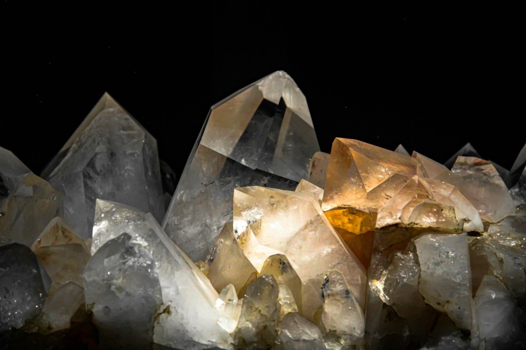 Clear and amber quartz crystals against a dark background