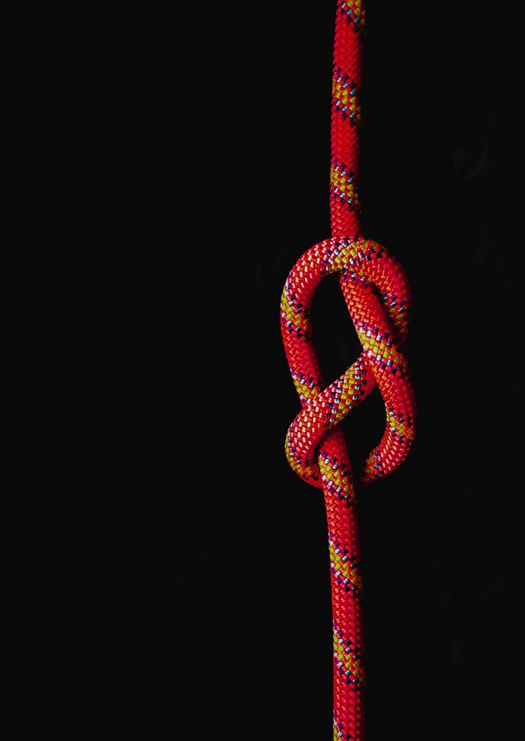 A white and red cord tied in a knot against a black background