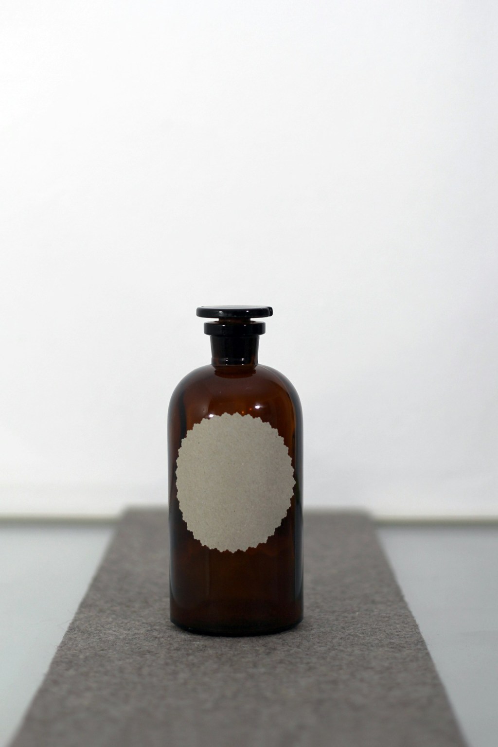 A single amber glass bottle with a dark, moody backdrop, the kind of bottle used to make a witch bottle