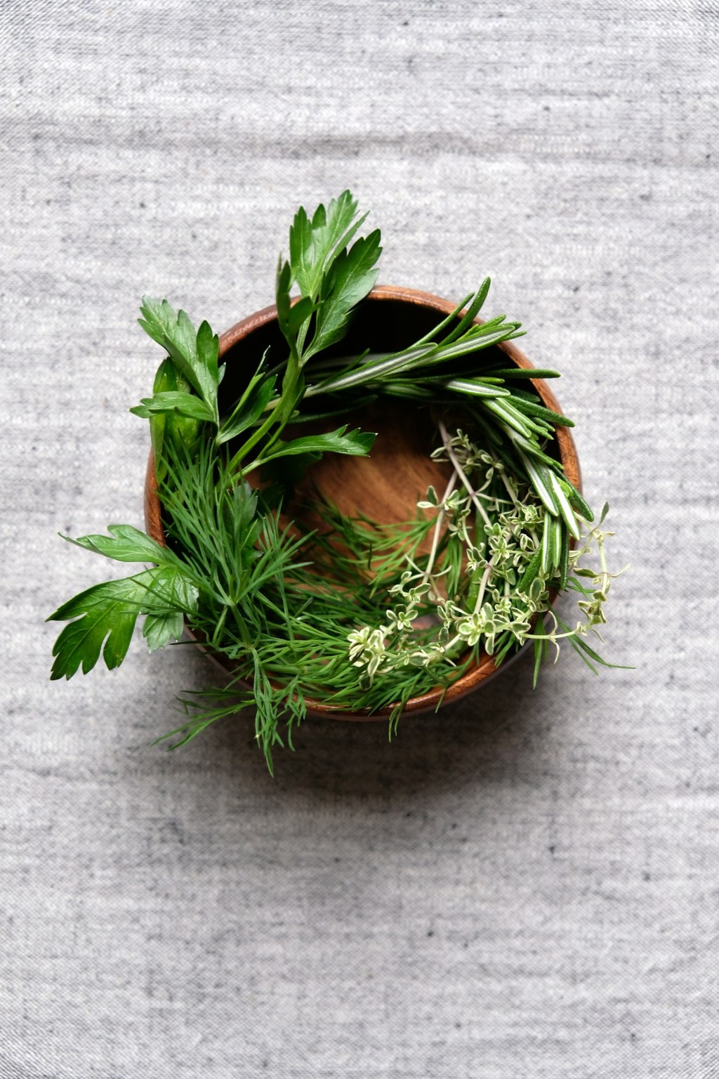 Witchcraft tools for beginners: a wooden bowl filled with dried herbs on a table