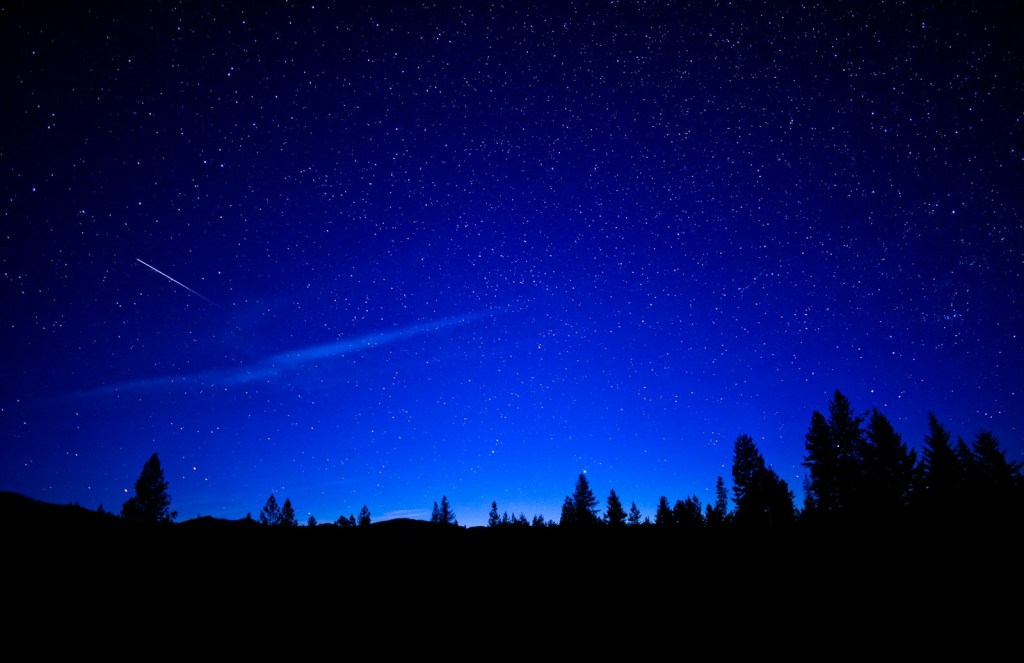 A shooting star streaking across a dark night sky full of stars